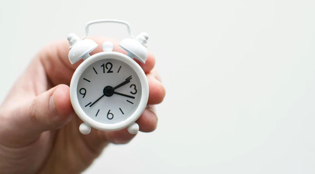 small alarm clock in hand